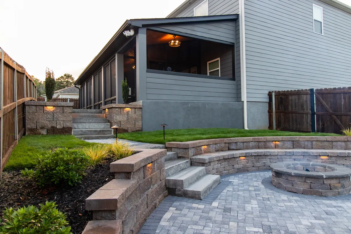 Full backyard build with covered patio, fire pit, retaining walls, and lit landscape at dusk, the Fulton Estate project by GreenTree Landscapes.